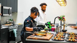 Una cocina moderna con armarios oscuros, estufa de acero inoxidable y una isla grande para preparación de alimentos.