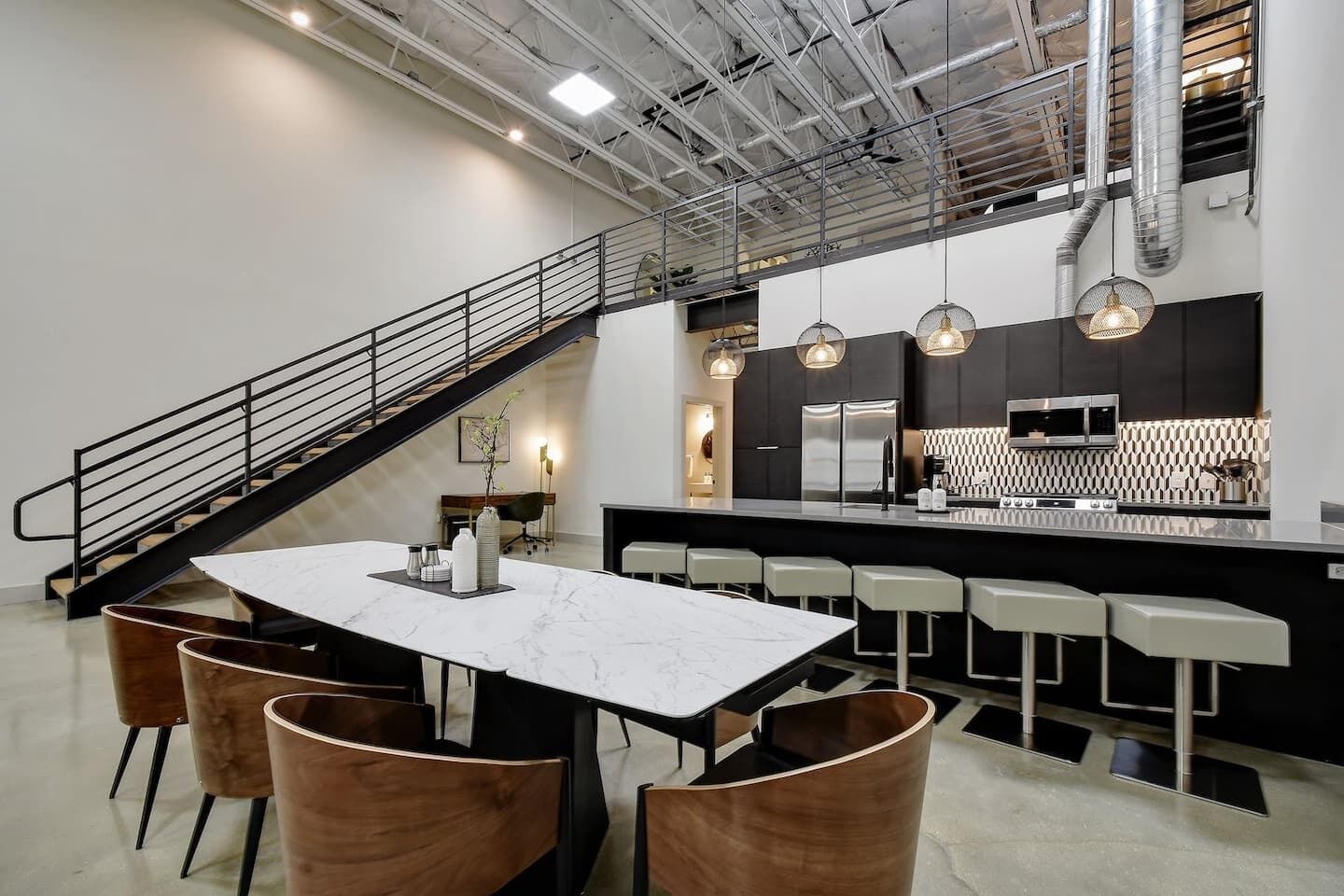 Una cocina moderna con una isla central, taburetes de bar e iluminación colgante.