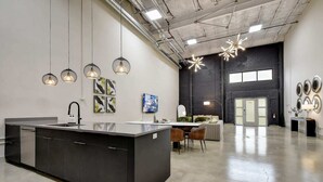 A modern kitchen with a central island, pendant lighting, and artwork on the walls. - 3BR Luxury Loft Near Downtown & Frost Bank Center (San Antonio)