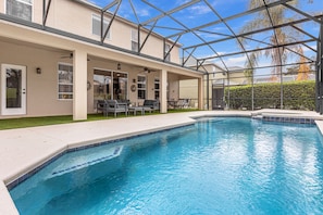 Piscina con un patio techado, ventilador de techo y vista a una palmera.