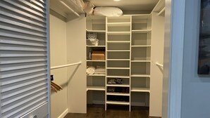 Un dressing avec des étagères blanches, un plancher en bois et une porte blanche.