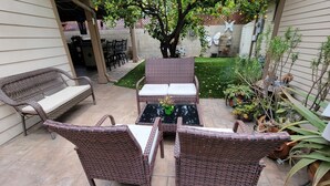 Une terrasse extérieure avec des meubles en osier, une petite table et une plante en pot.