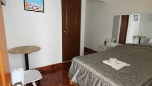 A hotel room with a bed, a small table, a chair, a mirror, and a television. - hospedaje pueblo viejo (San Luis de Cañete)