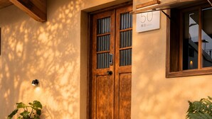 A wooden door with a sign, a potted plant, and a stone pathway leading to the entrance. - Twilight Stone (New Taipei City)