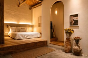 A bedroom with a bed, wooden steps, a rug, and two vases with flowers.