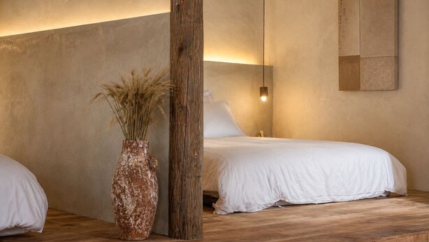 A bedroom with two beds, a wooden pillar, a vase with dried plants, and a wall-mounted light fixture. - Twilight Stone (New Taipei City)