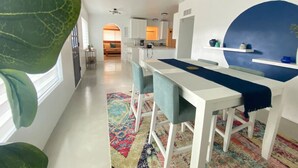 Une cuisine moderne avec des armoires blanches, un mur d’accent bleu et un ventilateur de plafond.