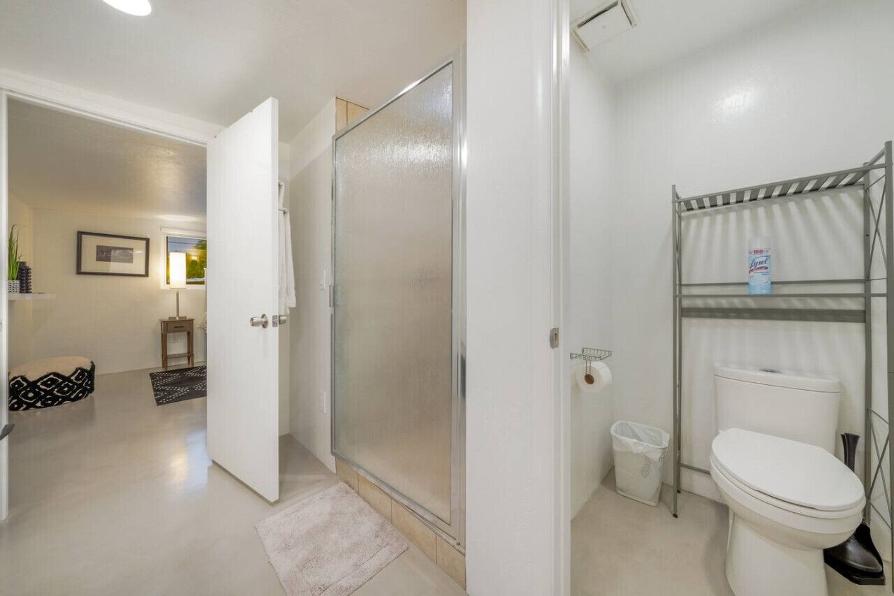 Ein Badezimmer mit Dusche, Toilette und Ablage für Toilettenartikel.