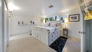 Une chambre à coucher avec un lit, des tables de chevet, une fenêtre et une porte.