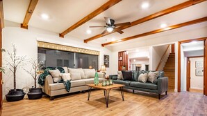 A spacious living room with wooden flooring, two sofas, a coffee table, and a ceiling fan. - Red Rock Falls Cabin•Yosemite 8mi•Game Room  •HotTub (Oakhurst)