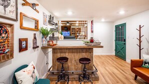 A modern kitchen with a bar area, wooden flooring, and a green door. - Red Rock Falls Cabin•Yosemite 8mi•Game Room•HotTub (Oakhurst)