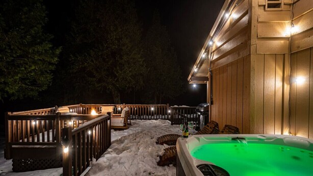 A wooden deck with a hot tub and seating area, surrounded by snow. - Red Rock Falls Cabin•Yosemite 8mi•Game Room•HotTub (Oakhurst)