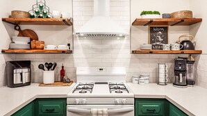 A kitchen with white cabinets, green drawers, a gas stove, a coffee maker, and various kitchen items on shelves. - Red Rock Falls Cabin•Yosemite 8mi•Game Room•HotTub (Oakhurst)