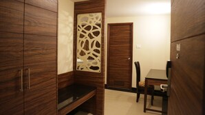 A room with wooden cabinets, a decorative panel, a door, and a table with chairs. - Rangalaya Royal (Katpadi)