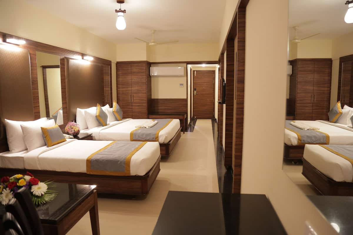 A hotel room with two beds, a flat-screen TV, a wooden wardrobe, and a mirror.