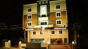 A multi-story hotel with a central stained glass window, multiple balconies, and a well-lit entrance. - Rangalaya Royal (Katpadi)