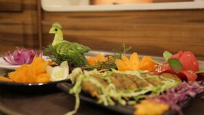 A variety of fresh vegetables and a decorative bird on a plate. - Rangalaya Royal (Katpadi)