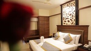 A hotel room with a bed, a nightstand, a telephone, and a decorative wall panel. - Rangalaya Royal (Katpadi)