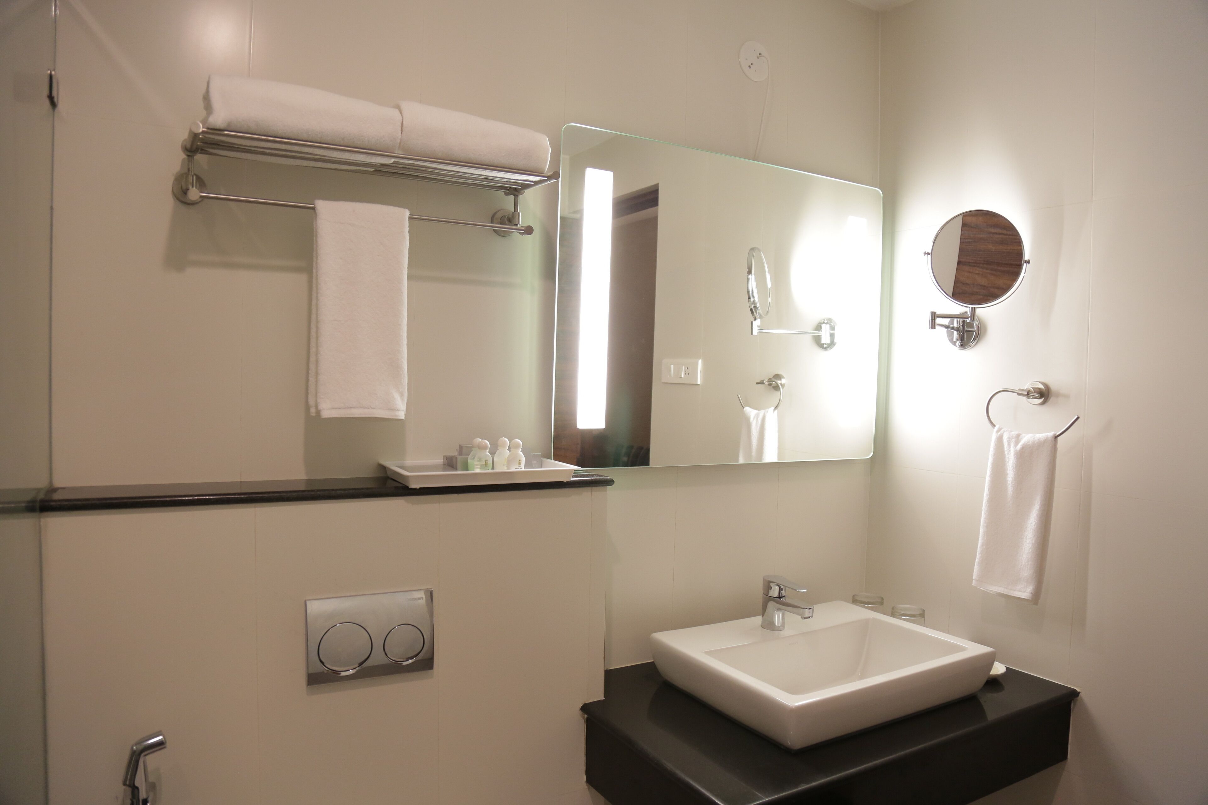 Une salle de bain moderne avec un grand miroir, un lavabo blanc et un porte-serviettes.