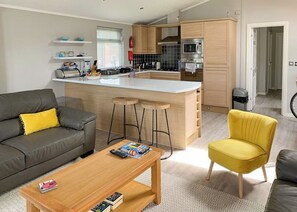 A modern kitchen with a central island, bar stools, and a dining area with a sofa and coffee table.