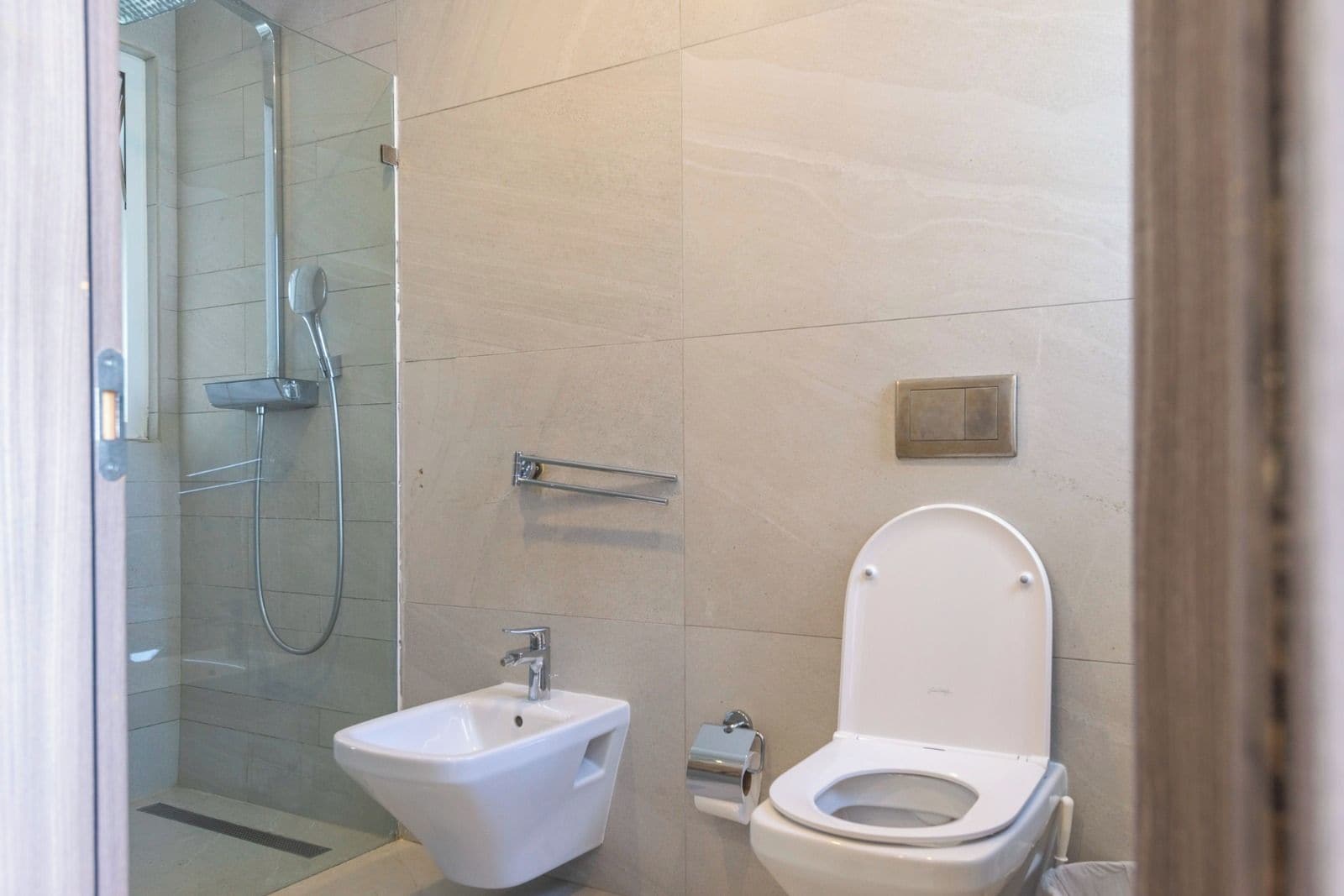 A modern bathroom with a glass shower enclosure, a bidet, and a toilet.