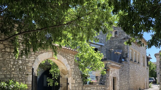 A stone building with an arched entrance, a balcony, and a sign indicating it is a rural lodging. - Gîte piscine** Chez Mémé de la Maréchale (Orgnac-l'Aven)