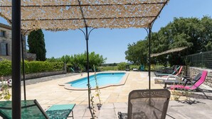 A swimming pool area with lounge chairs and a pergola. - Gîte piscine** Chez Mémé de la Maréchale (Orgnac-l'Aven)