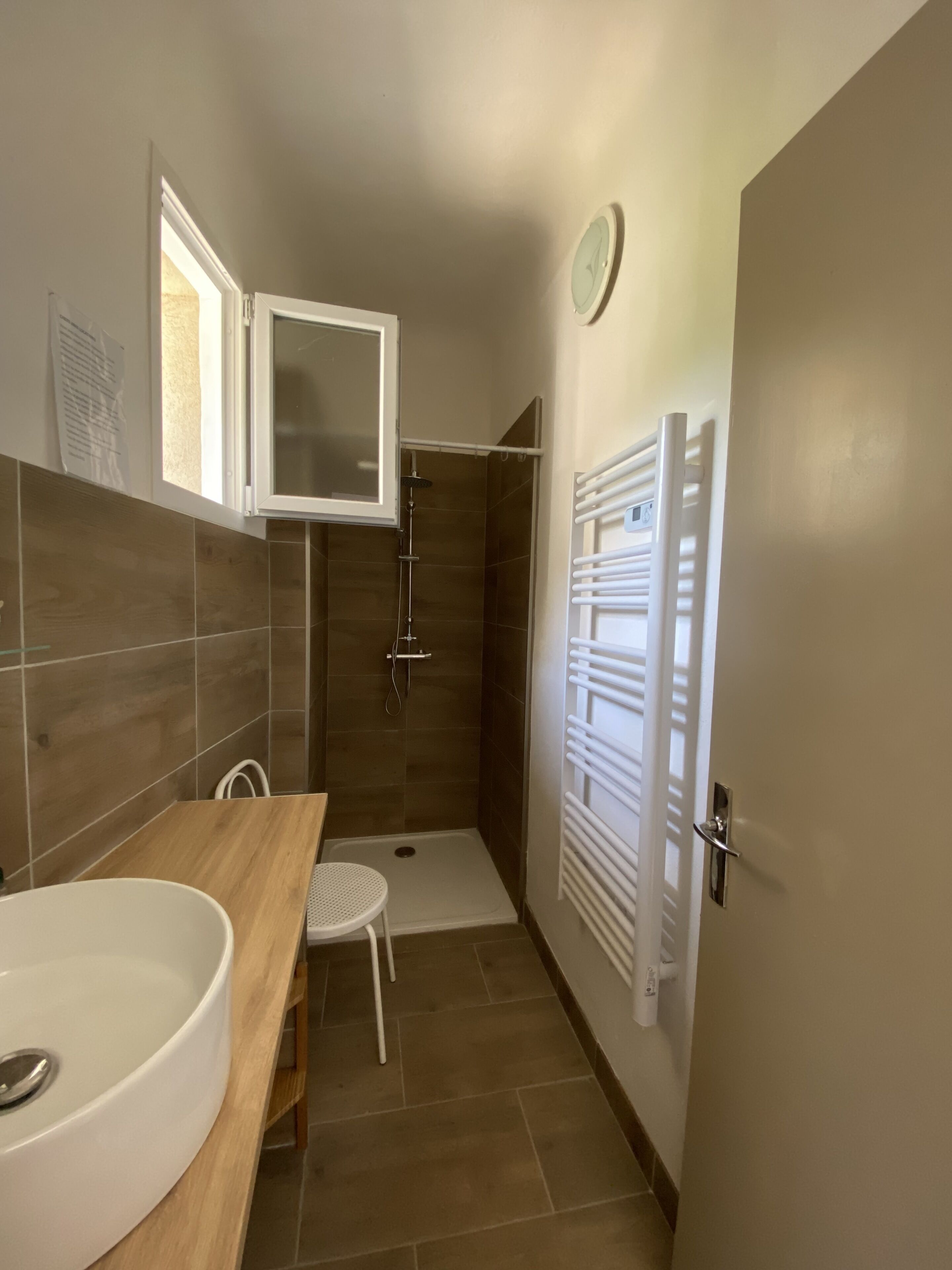 Un baño con ducha, lavamanos y un perchero para toallas.