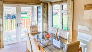 A dining area with a glass table, four upholstered chairs, and a bowl of fruit. - Borwick Heights 10 is ideal for a relaxing getaway. (Carnforth)