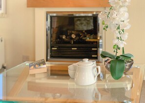 A glass table with a white teapot, a small card, and a potted orchid. - Borwick Heights 10 is ideal for a relaxing getaway. (Carnforth)