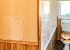 A bathroom with a wooden vanity, a white toilet, and a bathtub.