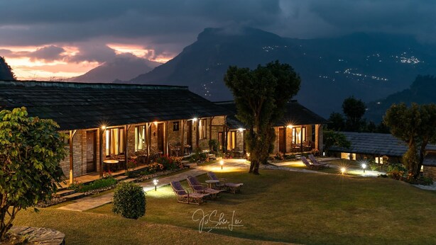 A hotel with multiple rooms, outdoor seating, and a view of mountains at dusk.