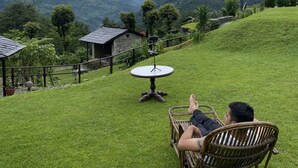 A person relaxing on a chair overlooking a mountainous landscape with a view of snow-capped peaks.