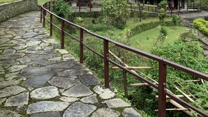 A stone pathway leading to traditional-style buildings with a mountainous backdrop.
