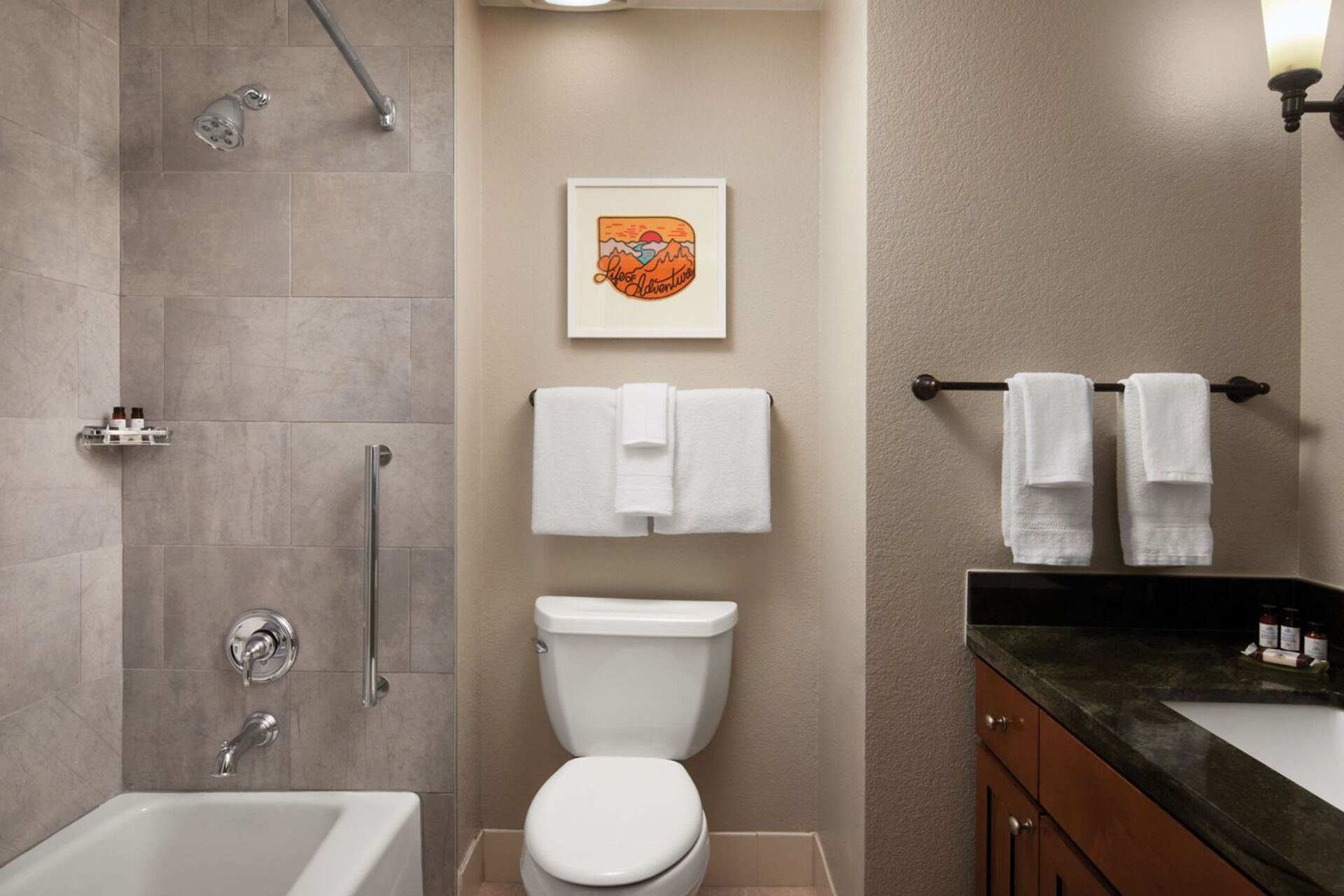 A bathroom with a shower, toilet, and sink. There are towels hanging on a rack.