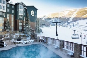 Hotel med swimmingpool, skilift og udsigt til et snedækket bjerg.