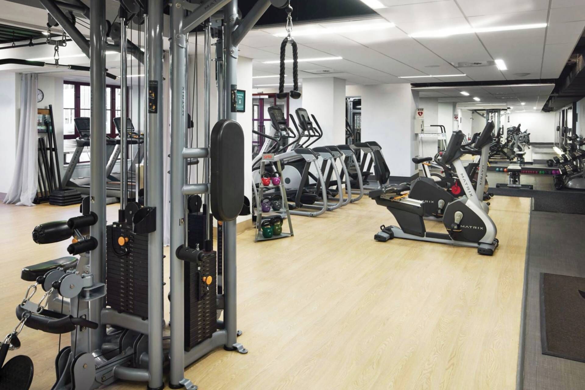 Een sportschool met diverse fitnessapparaten, waaronder loopbanden en krachtapparaten.