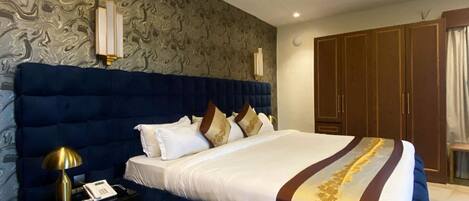 A bedroom with a large bed, a nightstand, a wardrobe, and a patterned wall.