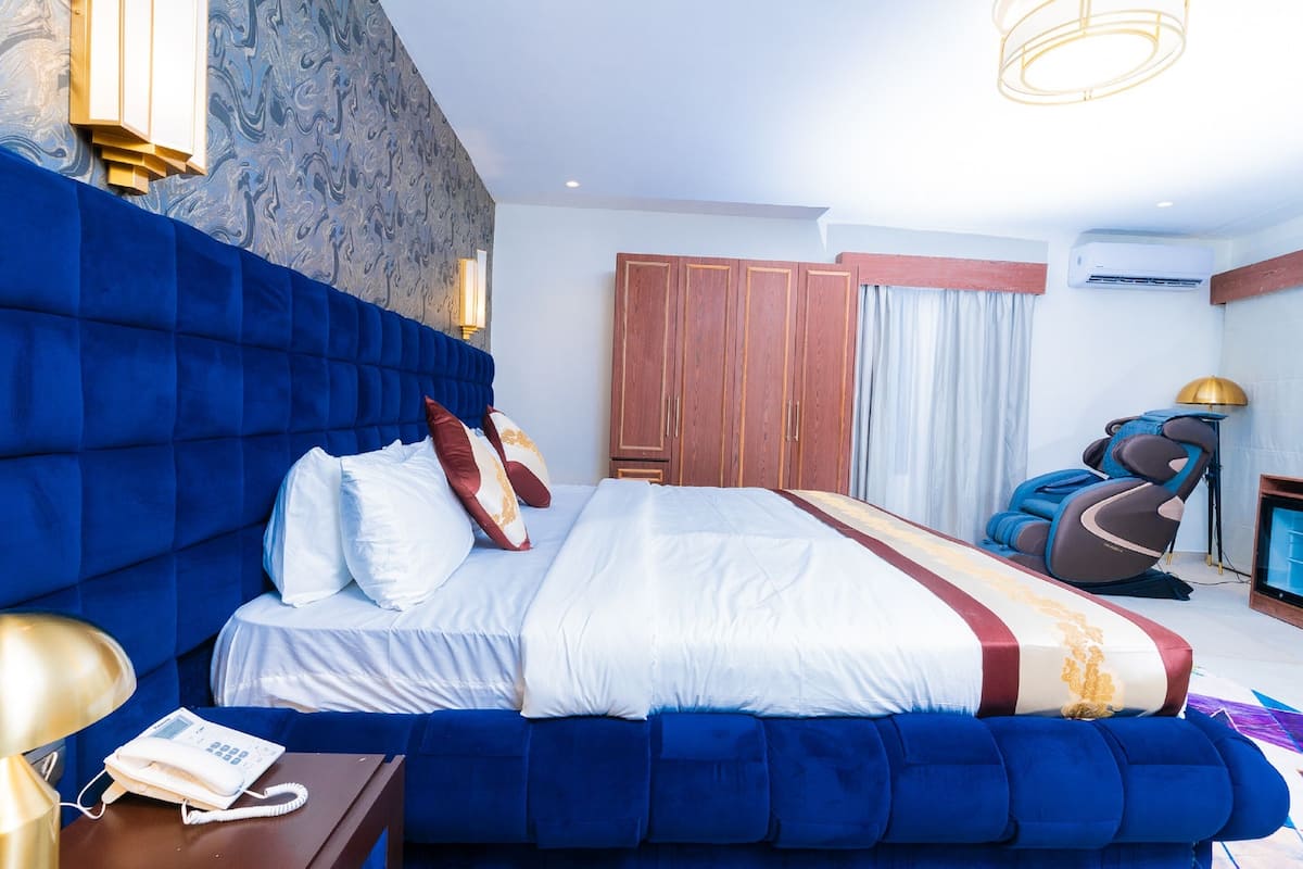 A hotel room with a large bed, a massage chair, and a TV.