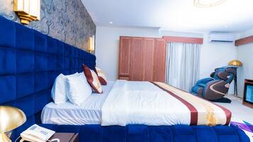 Quarto de hotel com uma cama grande, uma cadeira de massagem e uma televisão.