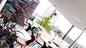 Een moderne eetruimte met witte tafels en stoelen, waarvan sommige oranje kussens hebben.