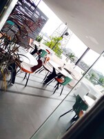 Un comedor interior moderno con mesas y sillas blancas, algunas con cojines naranja.