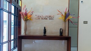 Een receptiebalie bij het Terraform Hotel met twee vazen decoratieve planten en een beeld.