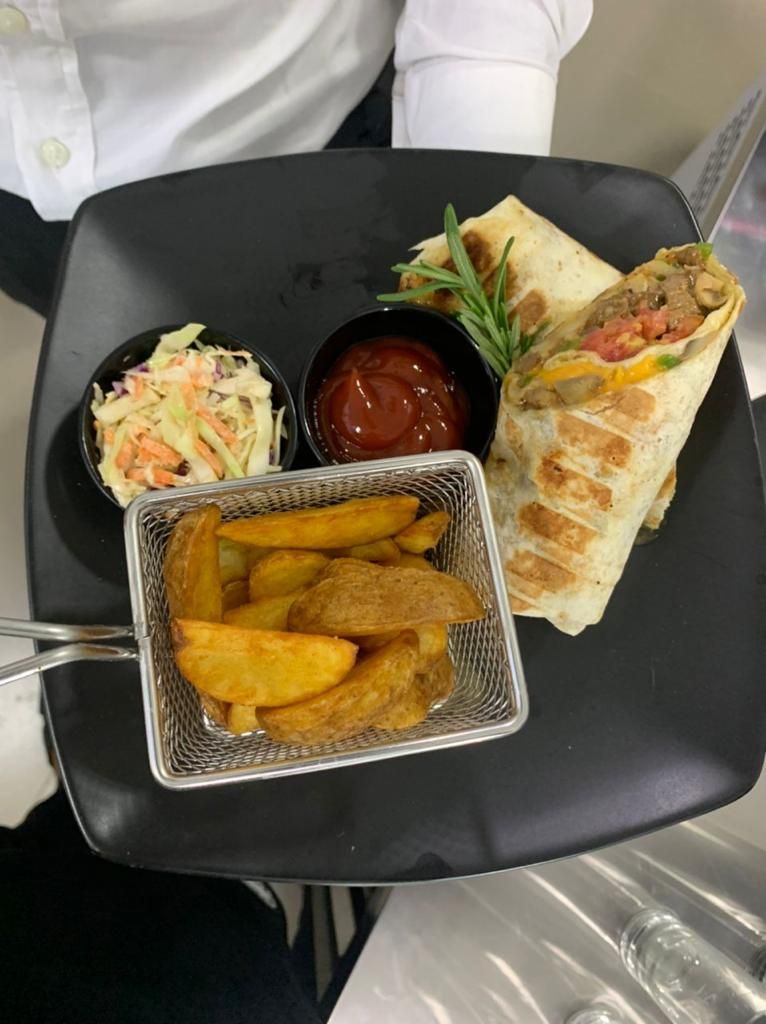 Un plateau avec un sandwich, une salade de chou, du ketchup et des frites.