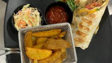 Un plateau avec un sandwich, une salade de chou, du ketchup et des frites.