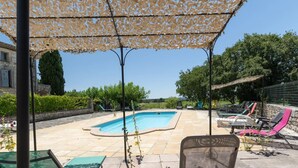 A swimming pool area with lounge chairs and a pergola providing shade.