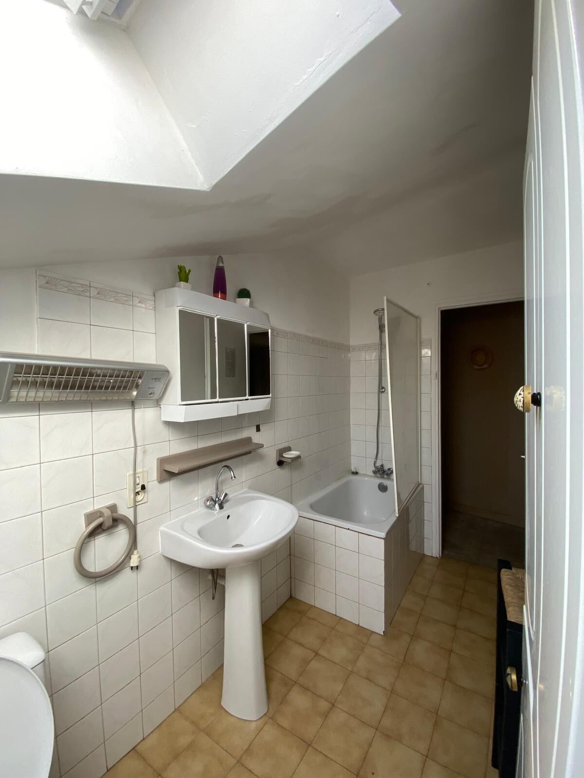 A bathroom with a white sink, a mirror, a shower, and a toilet.