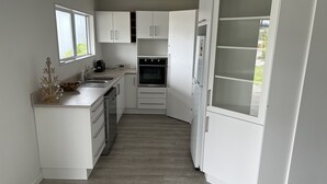 A modern kitchen with white cabinetry, a built-in oven, and a large window.