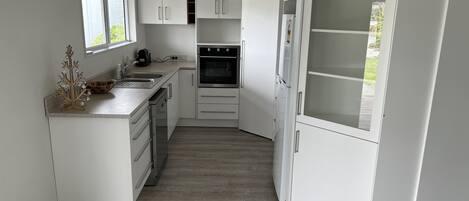 Ett modernt kök med vita skåp, en inbyggd ugn och ett stort fönster.