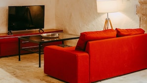 A cozy room with a red sofa, a television, and a chandelier.